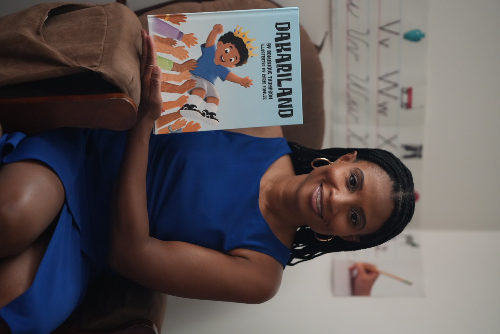 Dominique Thompson smiling and holding her children's book, Dakariland.